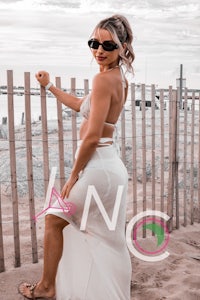 a woman in a white bikini posing in front of a fence