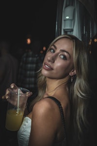 a woman holding a drink at a nightclub