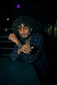 a man with dreadlocks sitting at a table at night