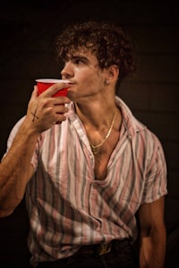 a man with curly hair drinking from a red cup