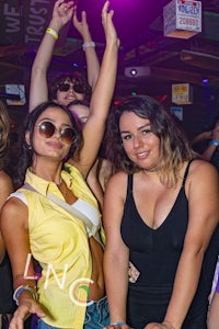 a group of girls at a nightclub with their hands up