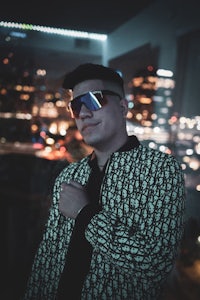 a man wearing sunglasses in front of a city at night