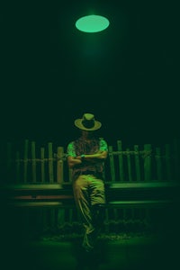 a man sitting on a bench under a green light