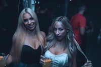 two women at a nightclub with drinks in their hands