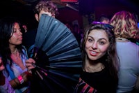 a woman holding a black fan at a party