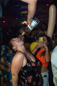 a woman drinking from a bottle at a party