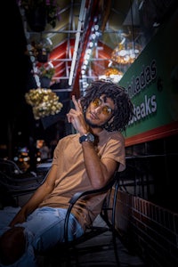 a man with dreadlocks sitting on a chair in front of a restaurant