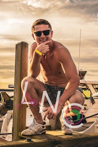 a man crouching on a dock next to a boat